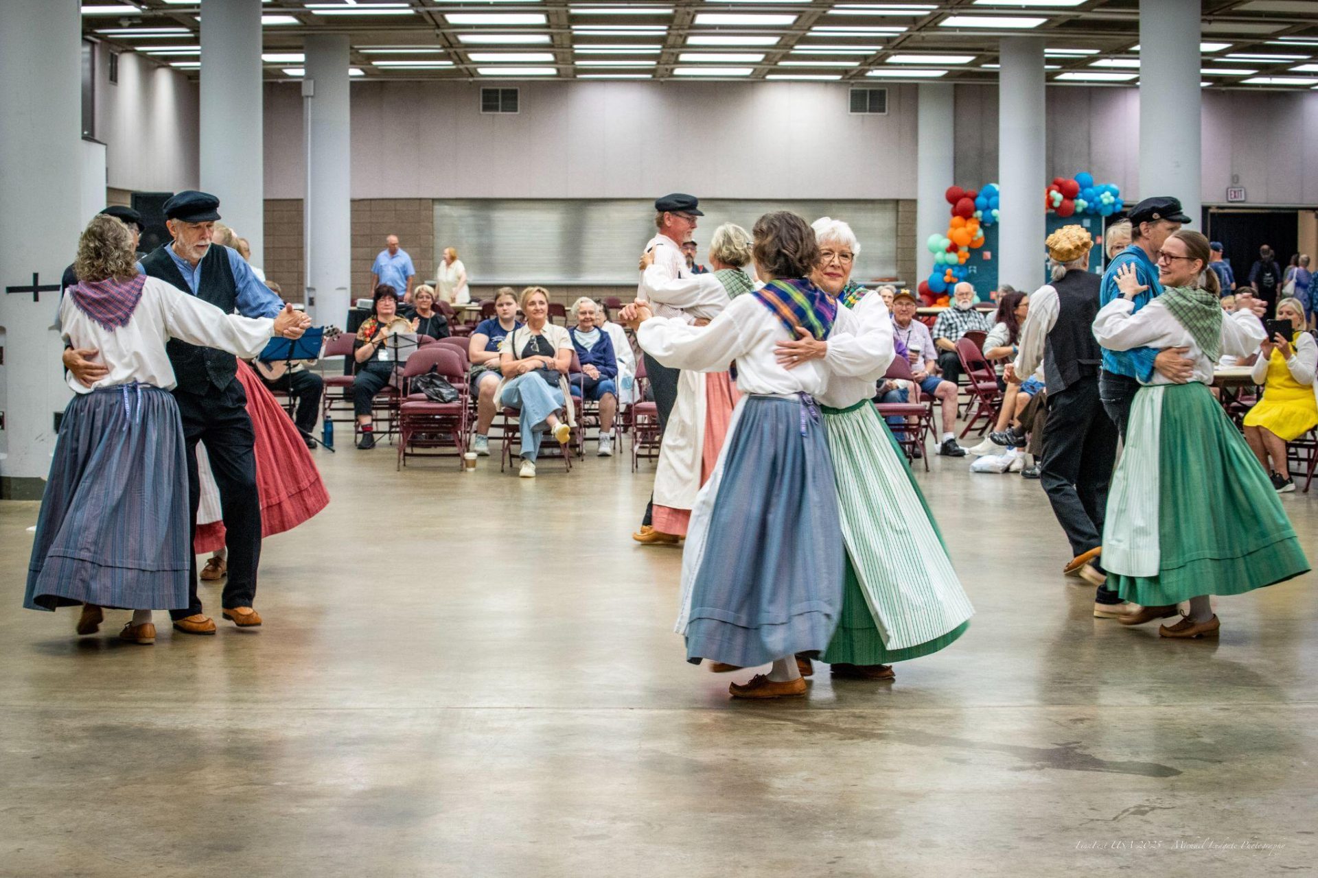 Folk dancers in traditional dress performing for a seated audience